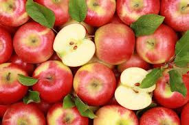 A collection of red Malus 'Gala' Apples with green leaves. One apple is cut in half, revealing its juicy Malus interior.