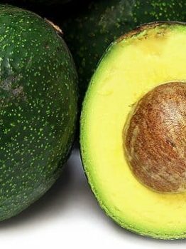 Close-up of whole and halved Persea 'Reed' Avocado 4L Pot revealing the seed and creamy green flesh.
.