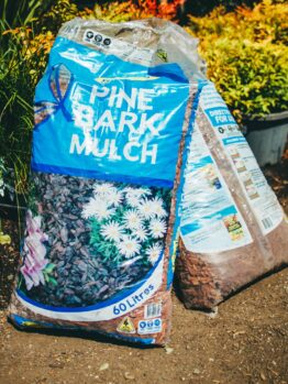 A bag of Searles Mulch Pine Bark 60L sitting on the ground.