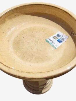 A round, beige birdbath filled with water, featuring a Sorrento Birdbath Cream 46x60cm label inside.