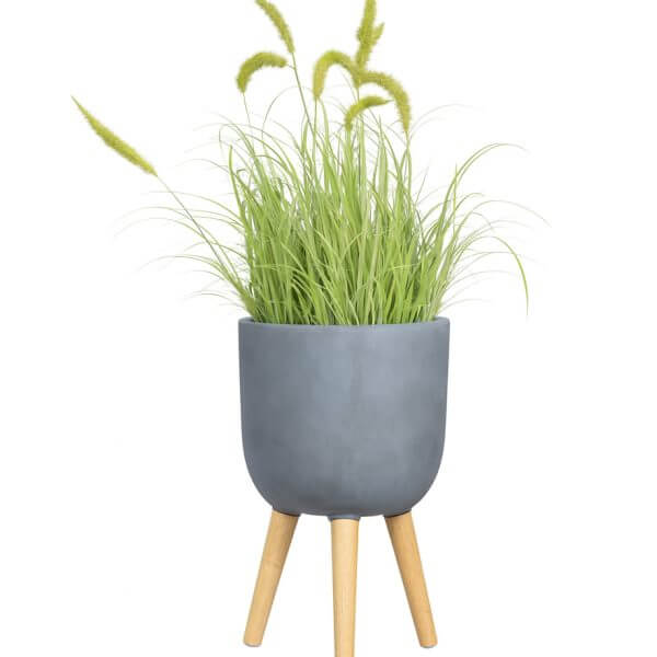 A GardenLite Egg Planter with Legs Brushed Concrete M 39x38cm holds tall, green ornamental grass with feathery seed heads, isolated on a white background.