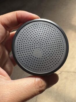 A hand holds the Hose Nozzle Water Breaker 400 Hole—black plastic head only—with a round, perforated front grille resembling its unique nozzle pattern.