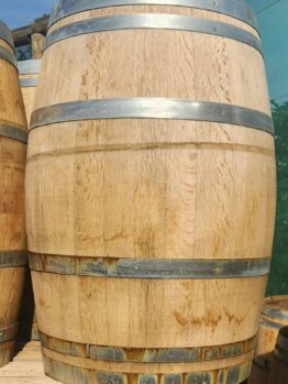 A Wine Barrel (Whole) with metal bands is standing upright on a wooden pallet outdoors.